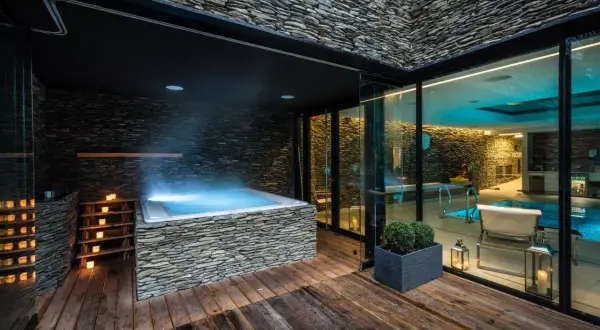 Luksusowy wrocław hotel z basenem i jacuzzi na zewnątrz. Kamienne wykończenia, drewniany taras i nastrojowe oświetlenie tworzą relaksującą atmosferę.