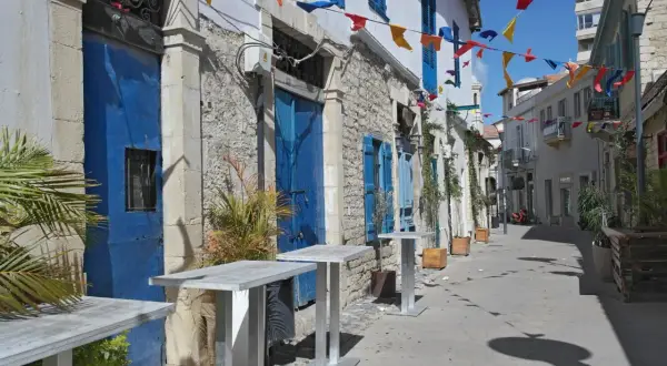 Urokliwe miasto na Cyprze z niebieskimi drzwiami i okiennicami, ozdobione kolorowymi chorągiewkami.