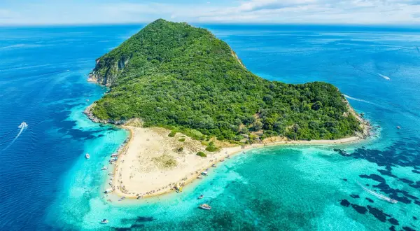 Malownicza wyspa Caretta Island na Zakynthos, z piaszczystą plażą i turkusową wodą, otoczona zielonymi wzgórzami.