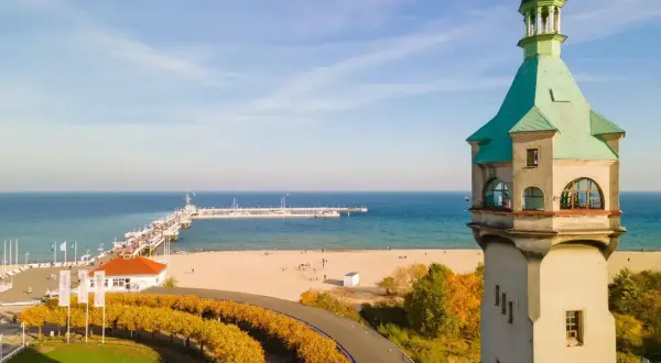 Widok na latarnię morską w Sopocie, plażę i molo w jesienny, słoneczny dzień.
