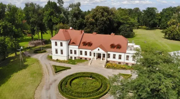 Piękny dwór stary Chotów otoczony zielenią, z zadbanym ogrodem i krętą ścieżką.