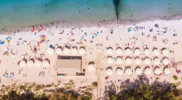 Idealne miejsce na wakacje: plaża z parasolami i ludźmi, idealna dla szukających najlepszych hoteli nad morzem z pełnym wyżywieniem.