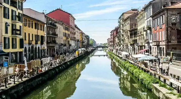 Malownicze Navigli w Mediolanie, z kolorowymi kamienicami po obu stronach kanału, odbijającymi się w wodzie.