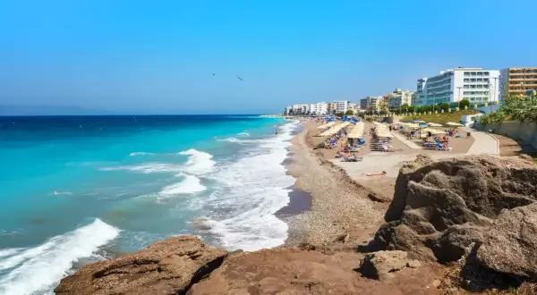 Słoneczna plaża na Rodos, z turkusową wodą i rzędami leżaków. To jedno z najpiękniejszych miejsc na wyspie, idealne na relaks.