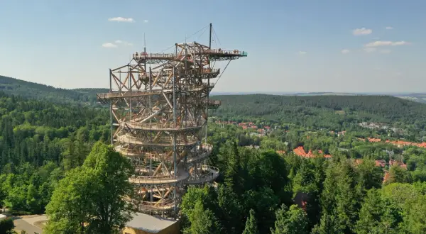 Wieża widokowa w Szklarskiej Porębie, przypominająca spiralny deptak, wznosi się nad zielonymi lasami i miastem.