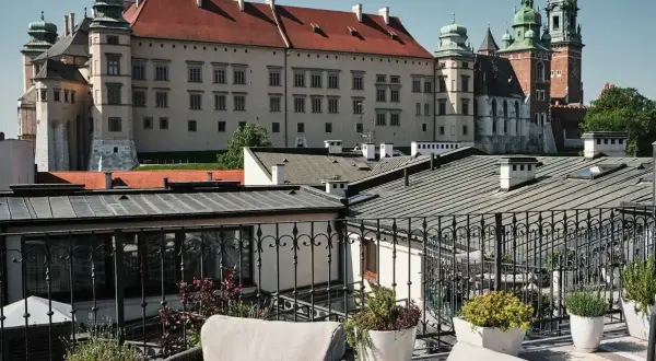 Widok z tarasu krakowskiego hotelu spa na Wawel. Wygodne fotele i rośliny tworzą relaksującą atmosferę.