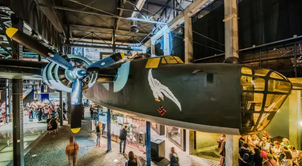 W Muzeum Powstania Warszawskiego opinie zwiedzających są pozytywne. Wnętrze z samolotem i grupami ludzi.