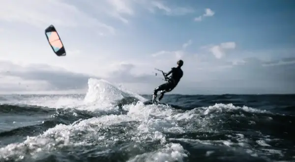 Kitesurfer w akcji, pokonujący fale. Dynamiczne sporty wodne w pełnym blasku.