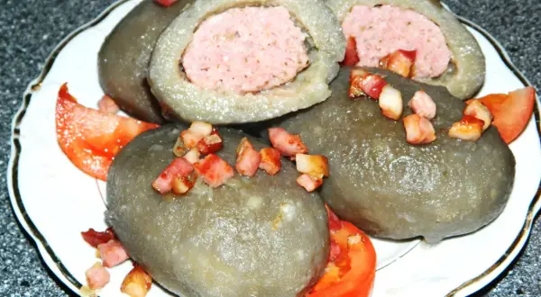 Cepelin z mięsem, okraszone skwarkami i pomidorem, wyglądają apetycznie.
