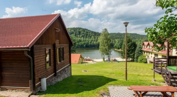 Drewniany domek nad jeziorem Śląsk, z placem zabaw i widokiem na las. Idealne miejsce na wypoczynek.