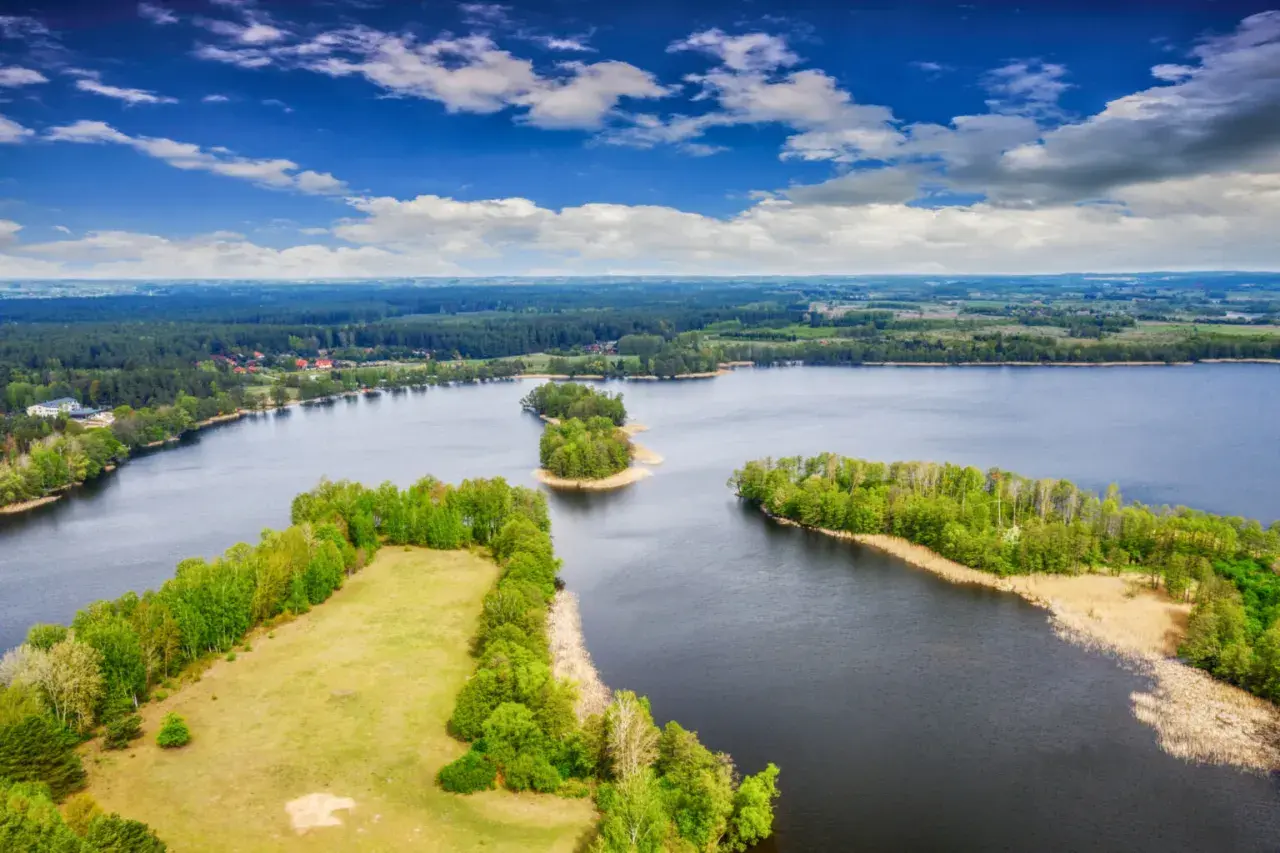 Malownicze wyspy na bałtyku, otoczone ciemną wodą i bujną zielenią lasów, pod błękitnym niebem z chmurami.