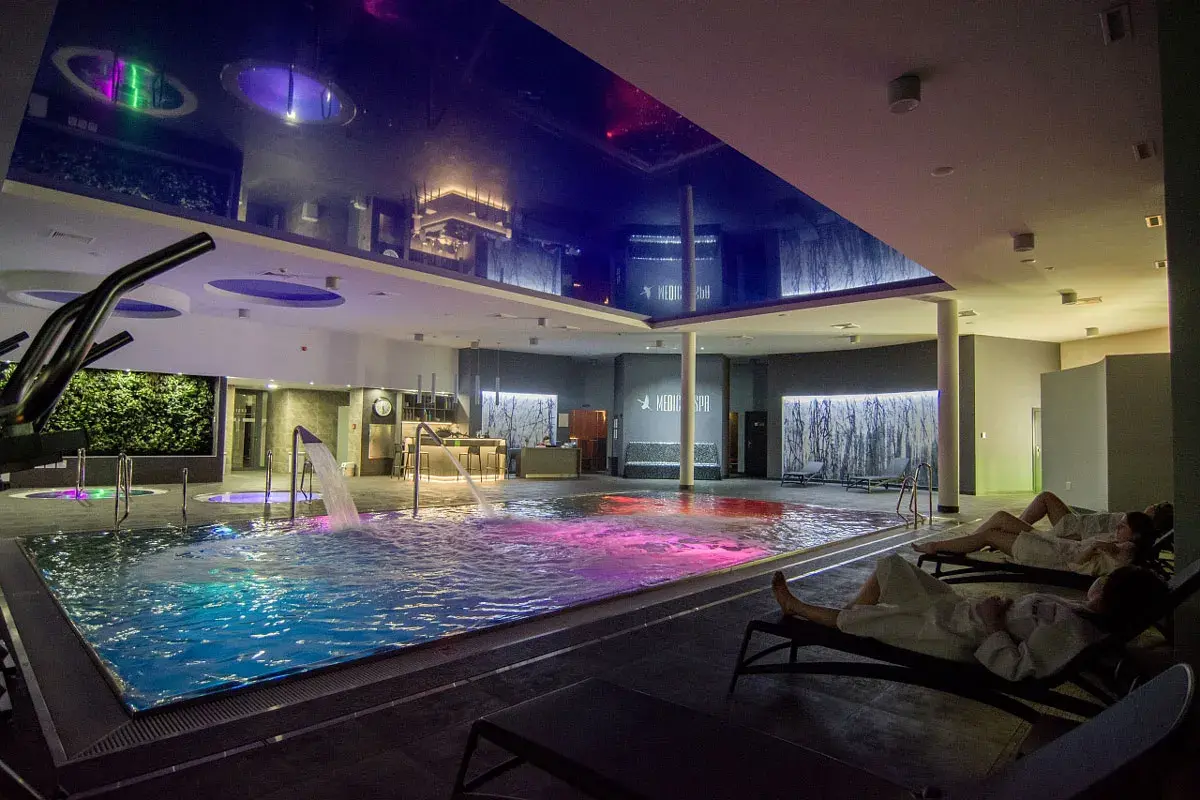 Relaks w hotelowym spa w Wielkopolsce. Basen z kolorowym podświetleniem, wodospady i leżaki.