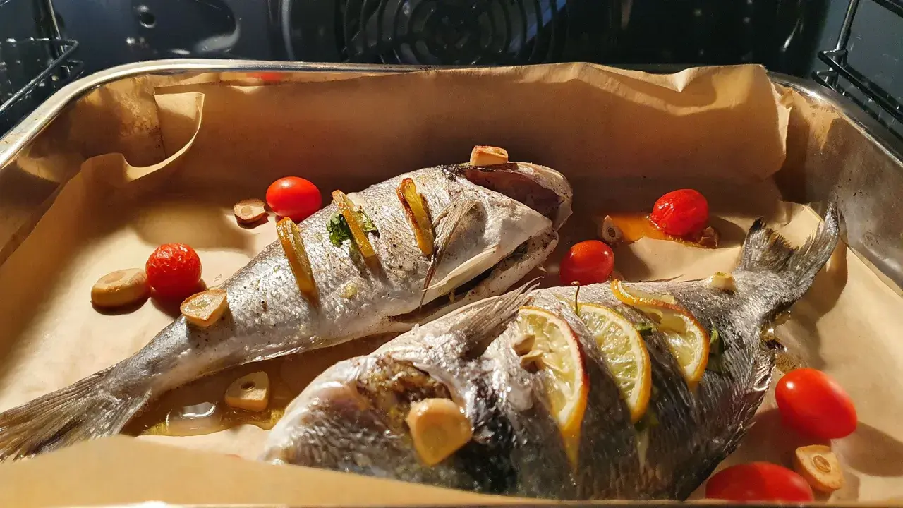 Dwie dorady pieczone z cytryną, czosnkiem i pomidorkami. Dorada co to za ryba? Pyszna ryba prosto z pieca!