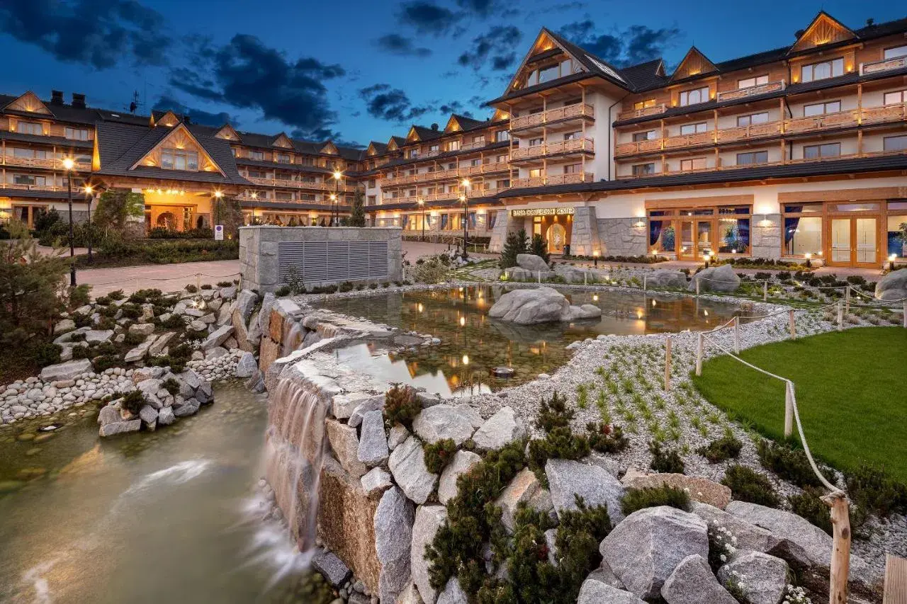 Elegancki hotel spa w górach z kaskadą wodną i stawem.
