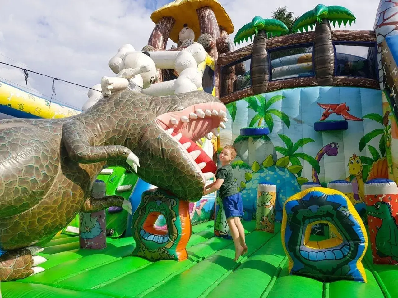 Chłopiec skacze na dmuchanym dinozaurze. Wspaniałe, ciekawe miejsca do 100 km od Katowic dla dzieci.