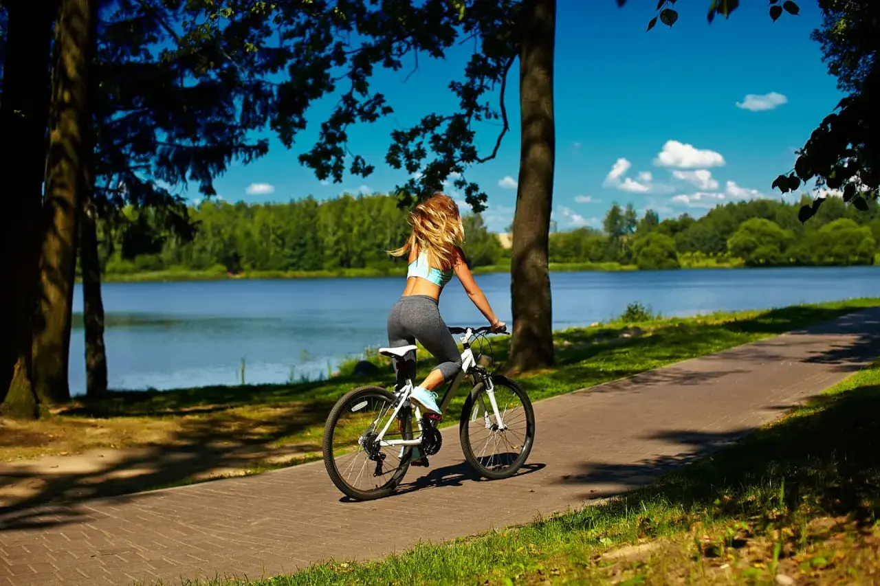 Kobieta na rowerze podziwia malownicze **trasy rowerowe Mazury** nad jeziorem.
