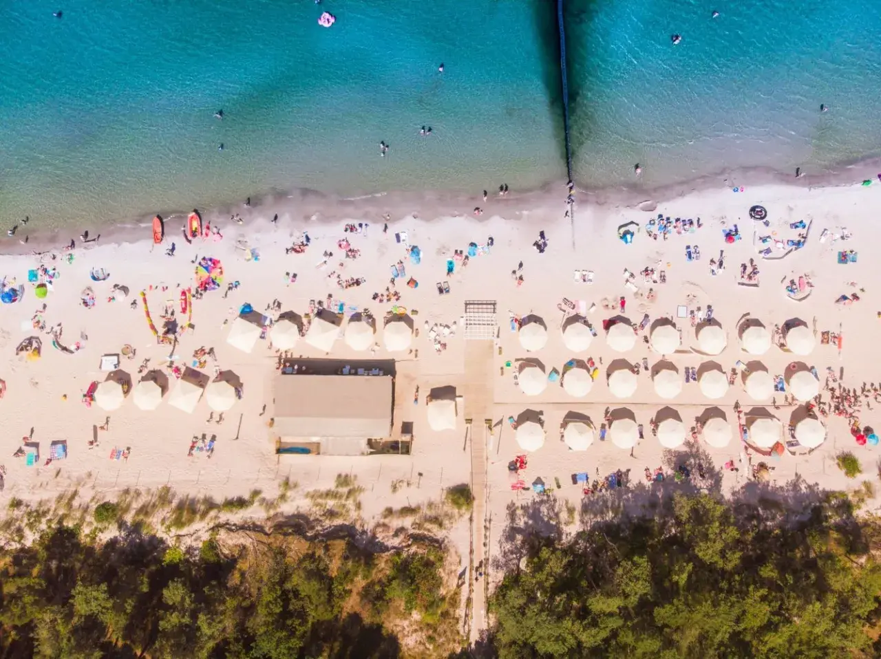 Idealne miejsce na wakacje: plaża z parasolami i ludźmi, idealna dla szukających najlepszych hoteli nad morzem z pełnym wyżywieniem.