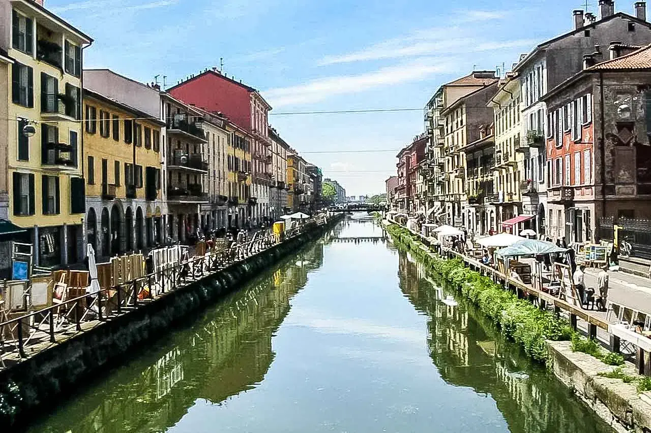 Malownicze Navigli w Mediolanie, z kolorowymi kamienicami po obu stronach kanału, odbijającymi się w wodzie.