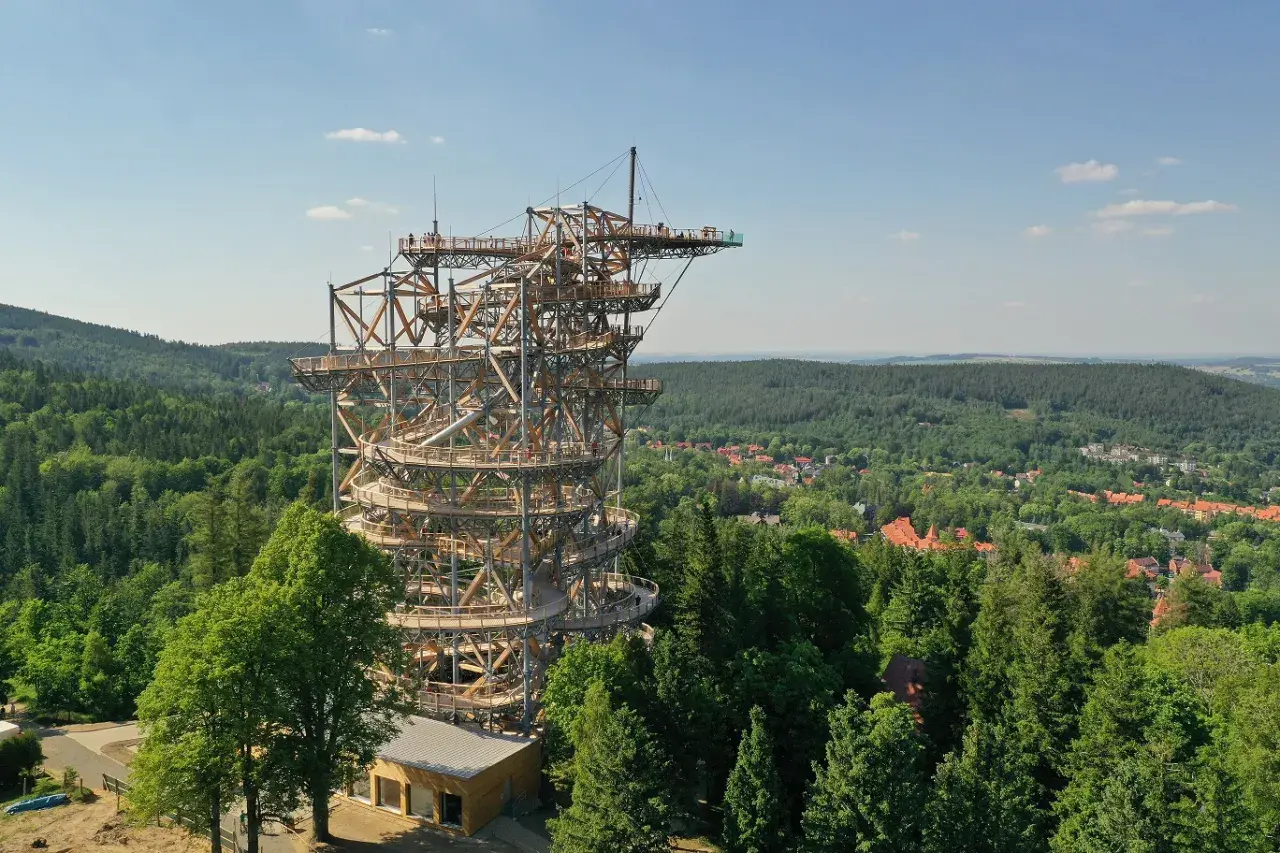 Wieża widokowa w Szklarskiej Porębie, przypominająca spiralny deptak, wznosi się nad zielonymi lasami i miastem.