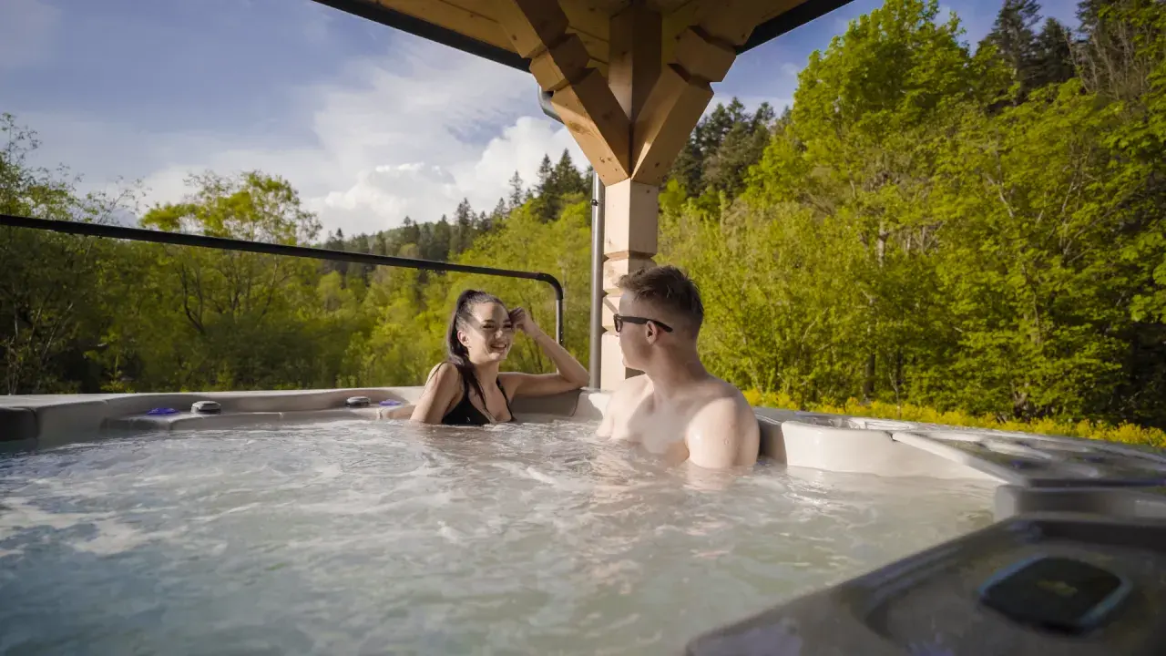Para relaksu w hotelowym spa w Bieszczadach: para cieszy się gorącą kąpielą na tle zielonych lasów.