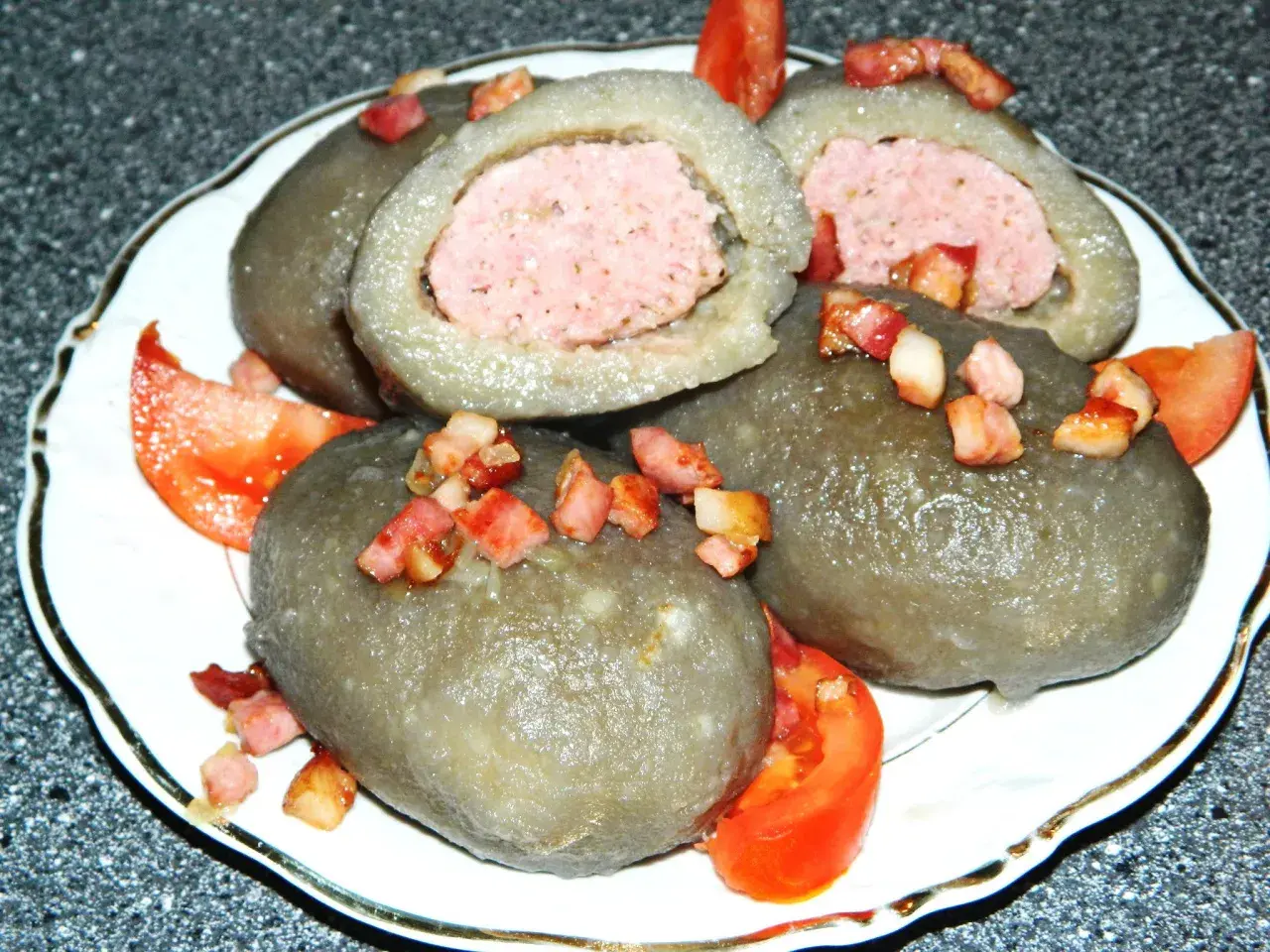 Cepelin z mięsem, okraszone skwarkami i pomidorem, wyglądają apetycznie.