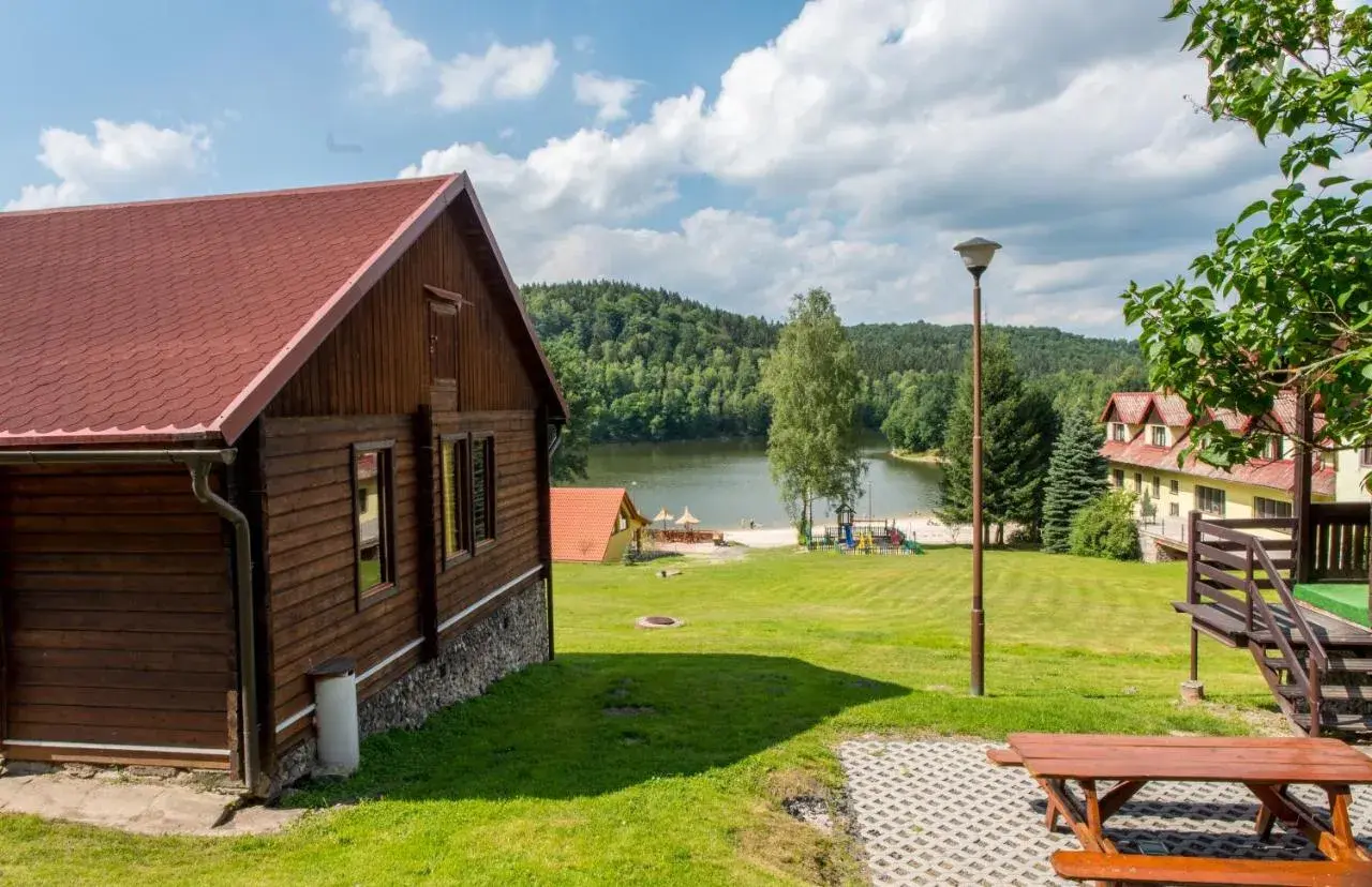 Drewniany domek nad jeziorem Śląsk, z placem zabaw i widokiem na las. Idealne miejsce na wypoczynek.