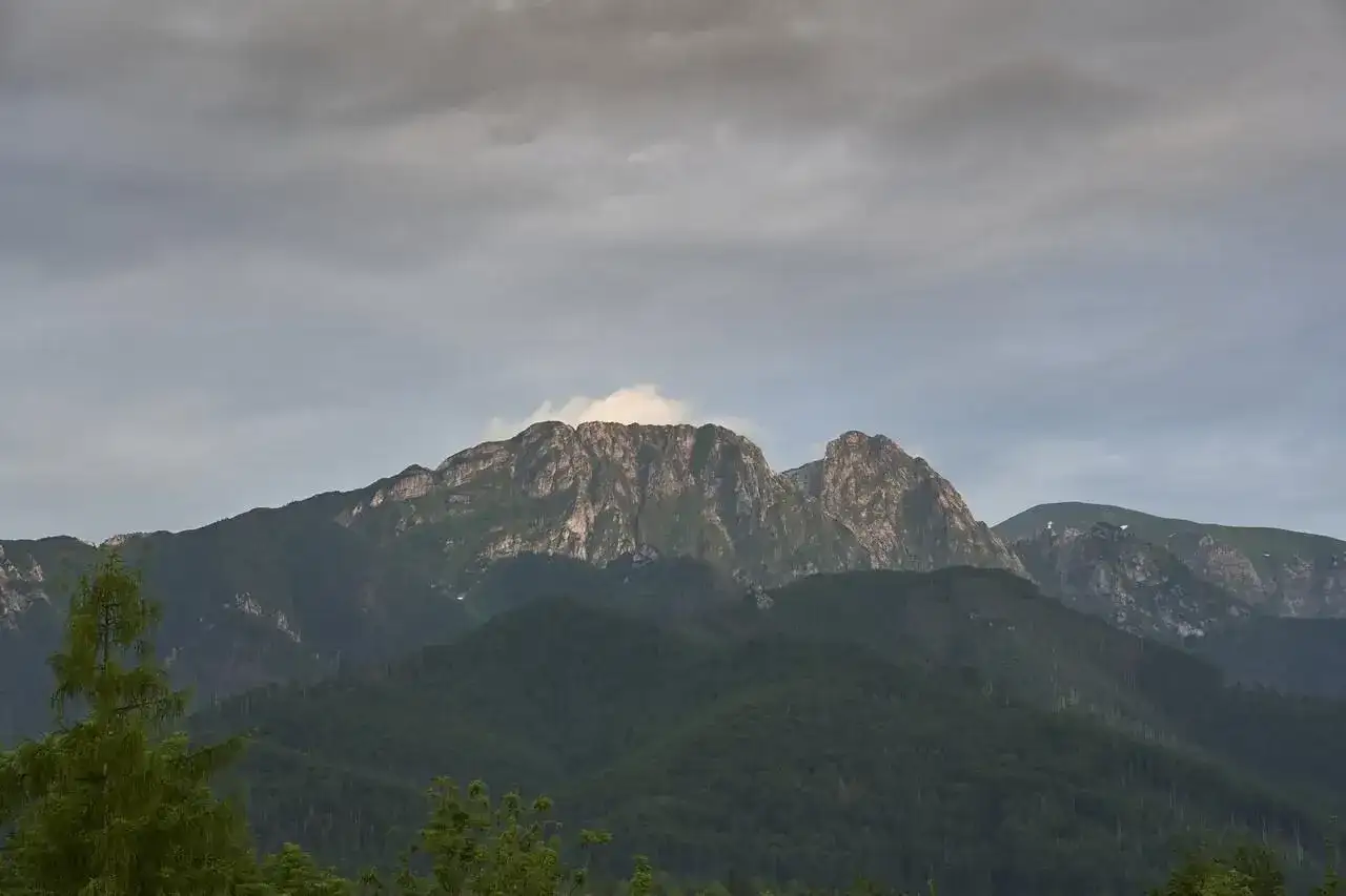 Giewont, śpiący rycerz Tatr, w chmurach. Góry o skalistych zboczach, porośnięte lasem.