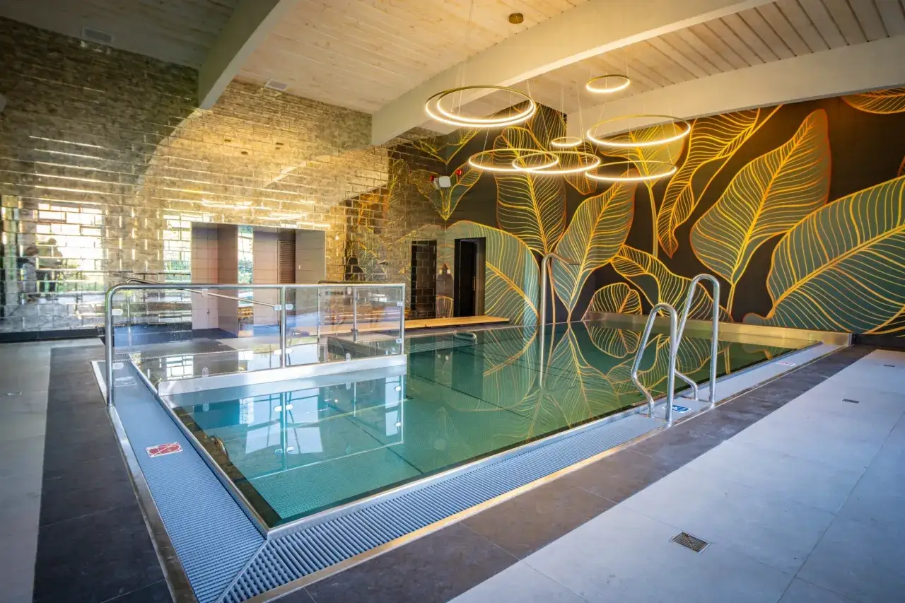 Nowoczesny hotel z basenem w Wielkopolsce. Eleganckie wnętrze z basenem, lustrzaną ścianą i designerską tapetą z liśćmi.