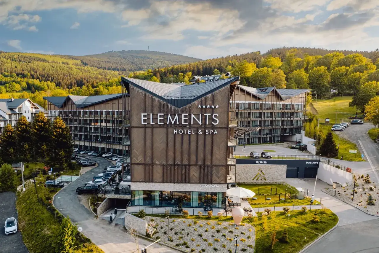 Nowoczesny hotel spa w górach, otoczony zielenią. Elegancka architektura i piękne widoki.