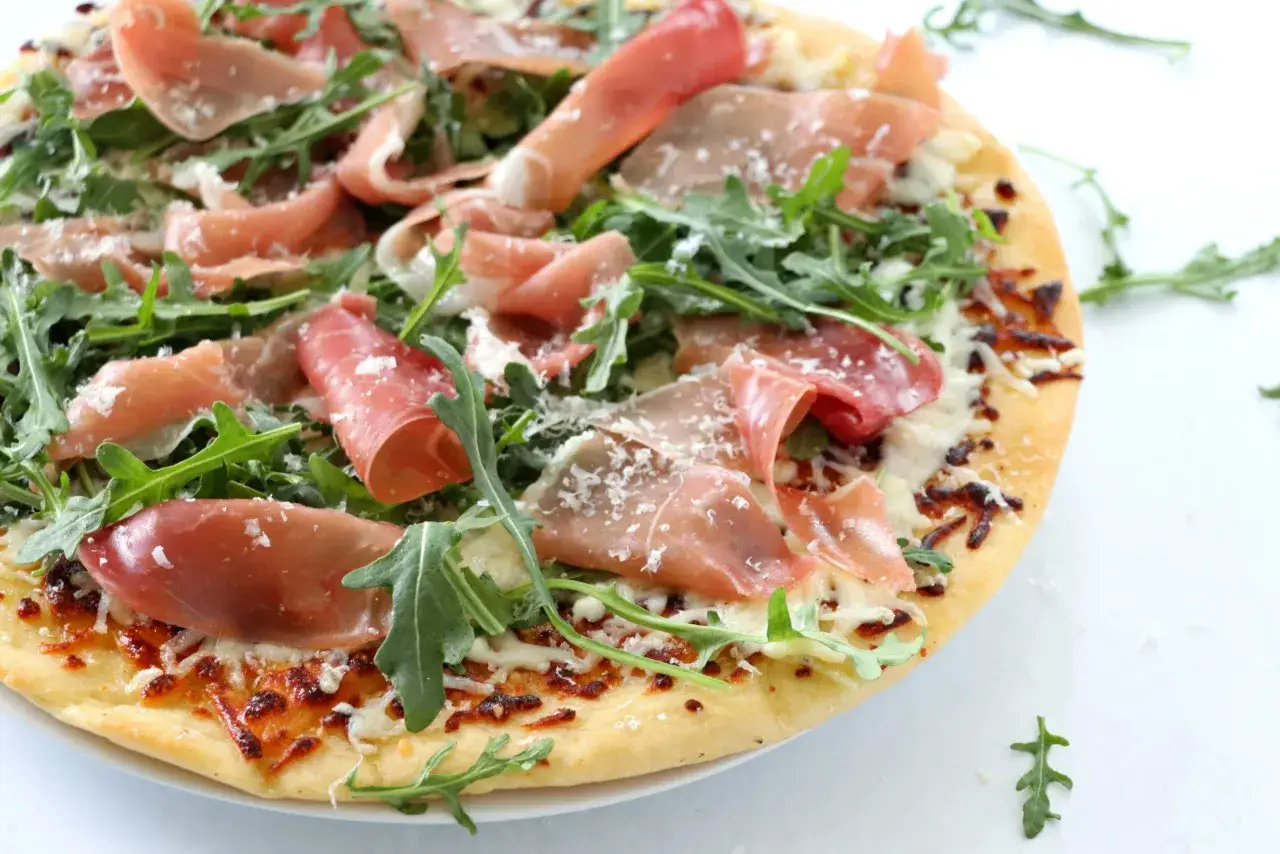 Pizza parma z rukolą i parmezanem, pachnąca włoskimi smakami.