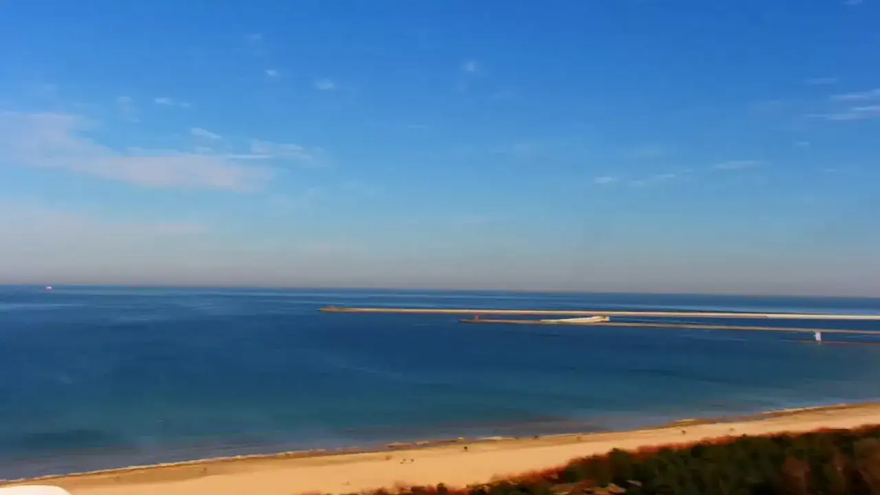 Piękna plaża i morze, a w oddali widać falochrony, które są jednymi z głównych promenada świnoujście atrakcje.