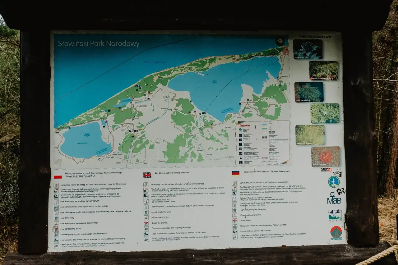 Mapa Słowińskiego Parku Narodowego z zaznaczonymi atrakcjami, jeziorami, morzem i szlakami.