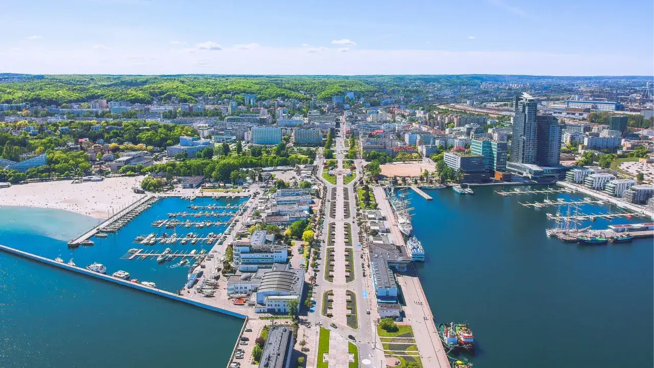 Gdynia stare miasto z lotu ptaka: port jachtowy, plaża, nowoczesne budynki i zieleń.