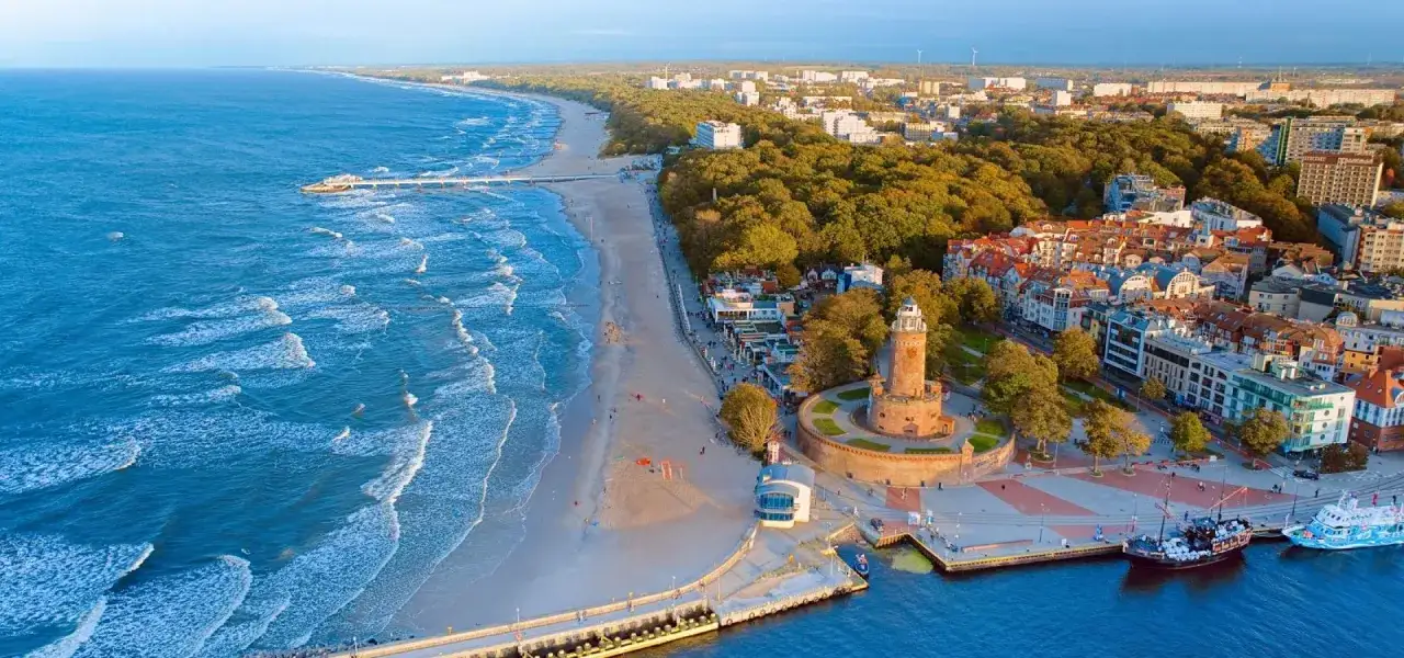 Widok na plażę, morze i latarnię morską w Kołobrzegu. Wspaniałe atrakcje w Kołobrzegu czekają na turystów.