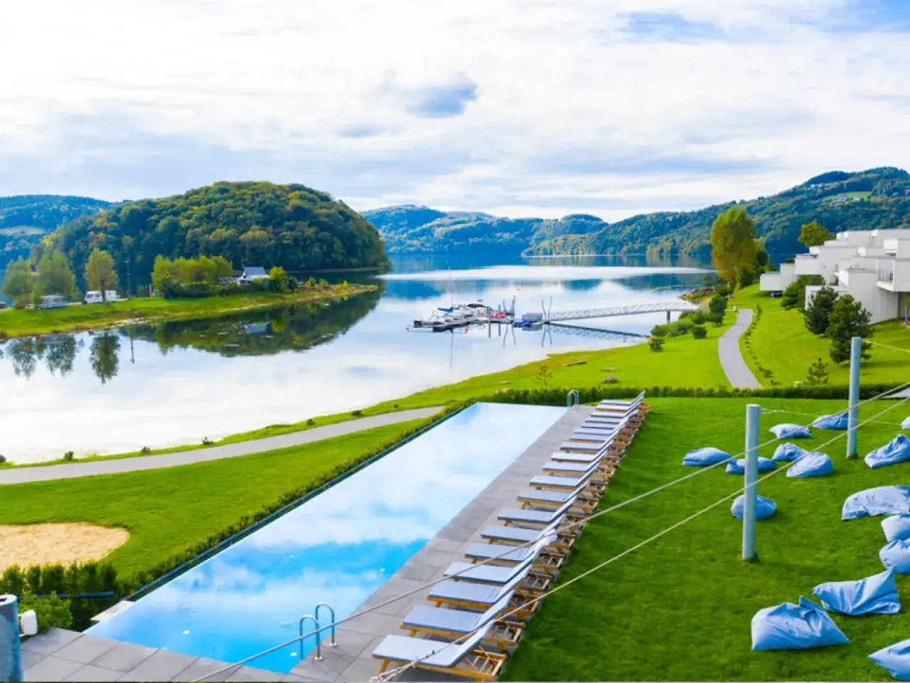 Nowoczesne hotele spa Polska nad jeziorem, z basenem infinity, leżakami i widokiem na góry.