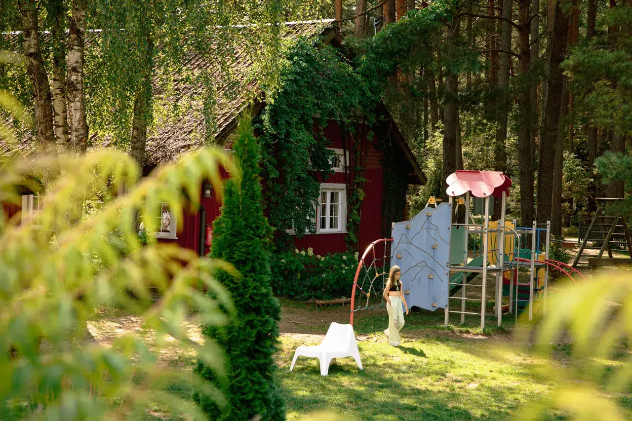 Dziewczynka bawi się na placu zabaw w otoczeniu lasu, idealne miejsce na mazury z dziećmi.