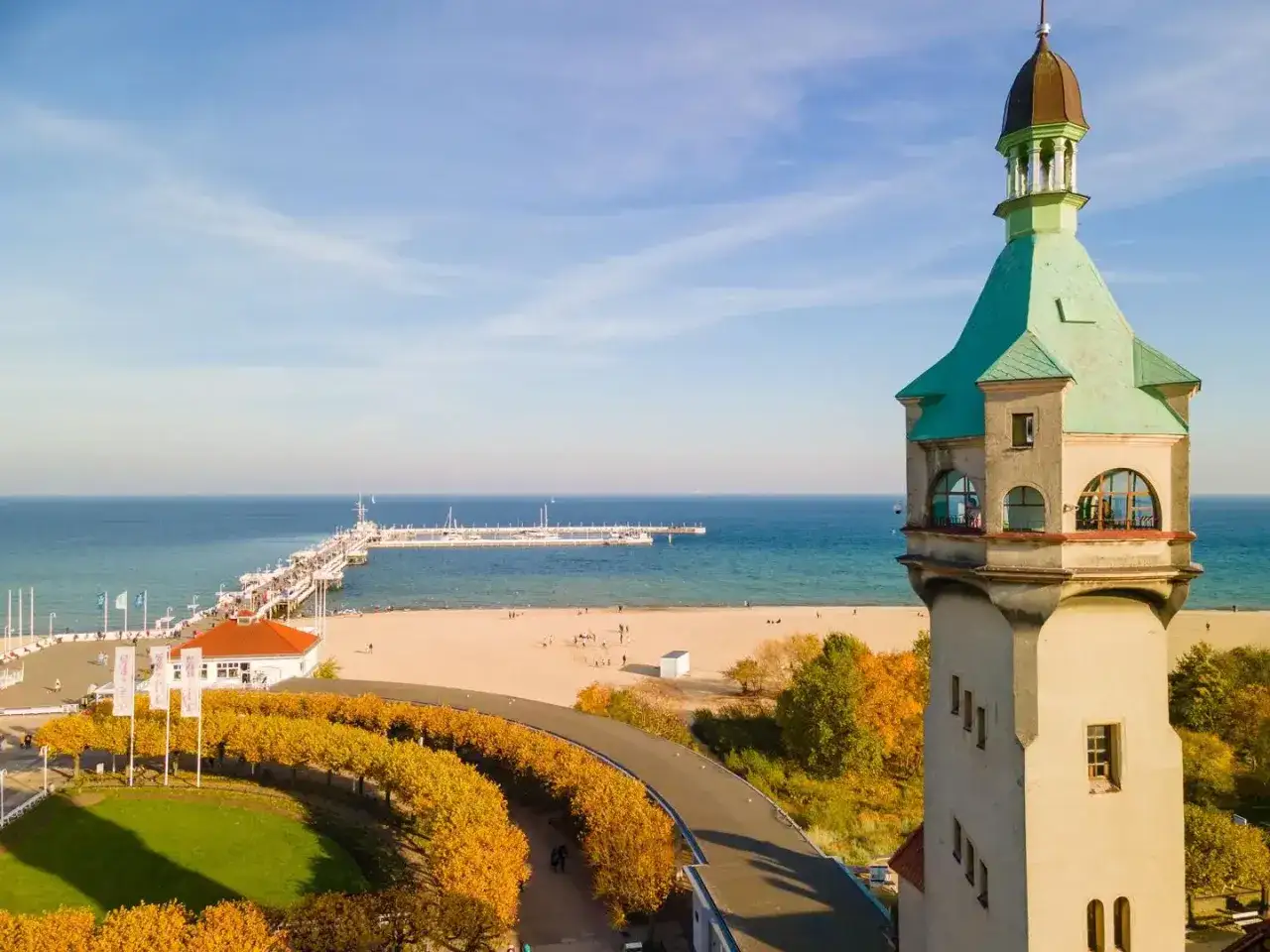 Widok na latarnię morską w Sopocie, plażę i molo w jesiennej scenerii.