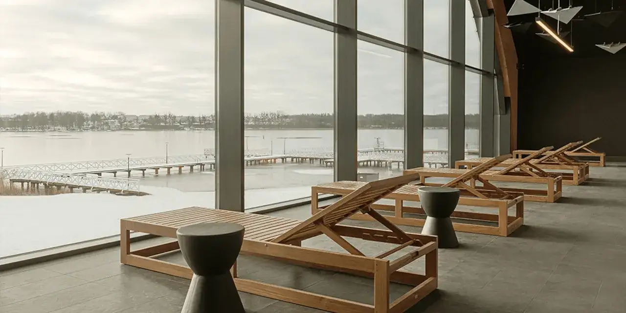 Drewniane leżaki w nowoczesnym hotelu spa lubelskie, z widokiem na zamarznięte jezioro i molo.