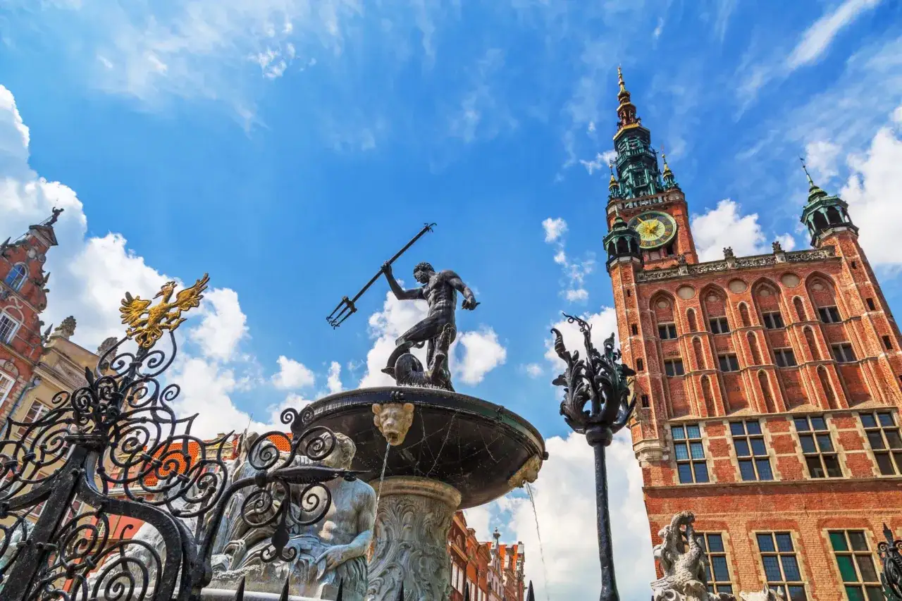 Fontanna Neptuna i Ratusz Głównego Miasta na tle błękitnego nieba z chmurami. Urokliwe Gdańsk Stare Miasto.