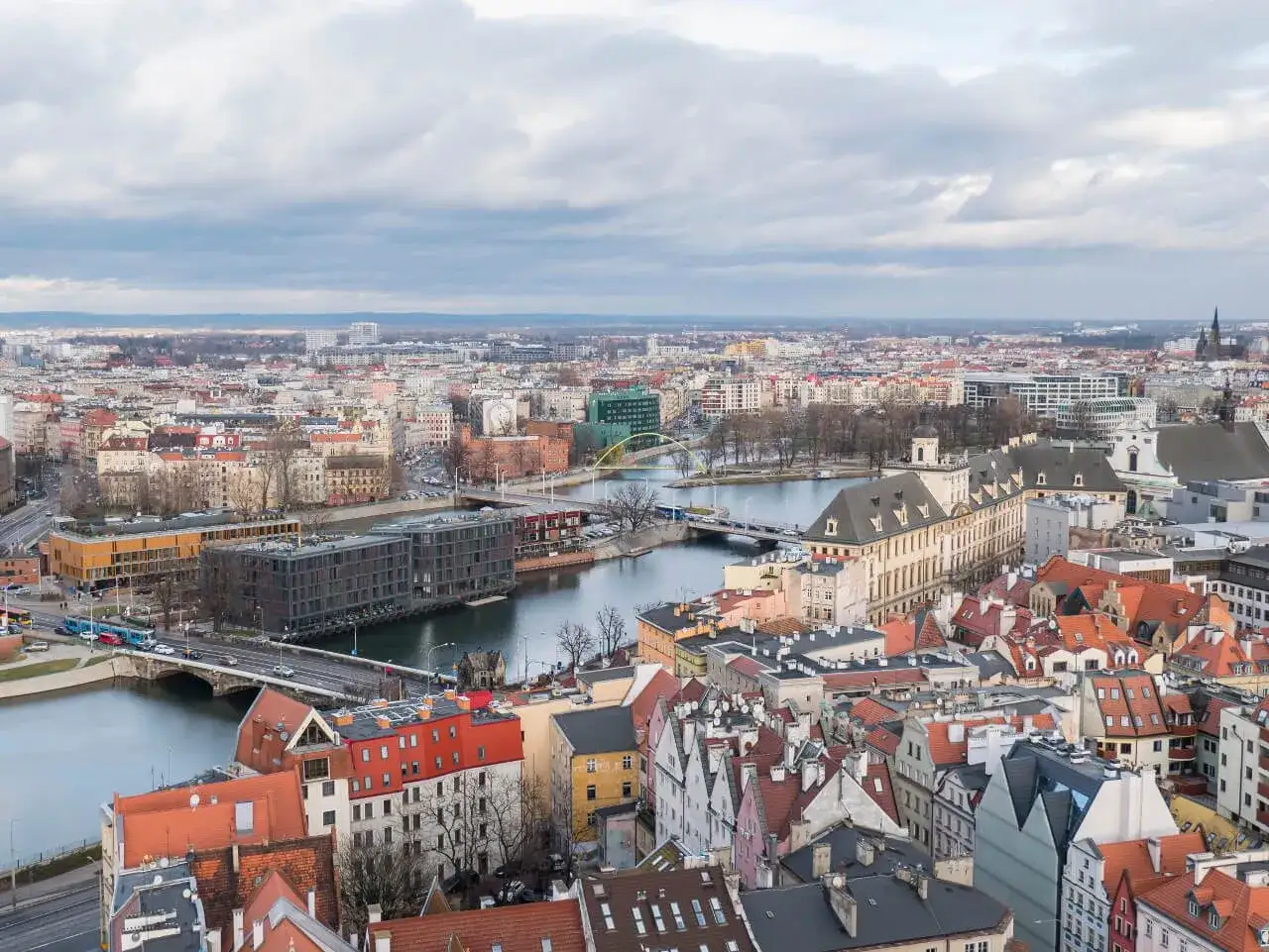 Widok na miasto z góry, rzeka, mosty i budynki. W oddali widać panoramę miasta, która przypomina widok z wież widokowych Dolnego Śląska.