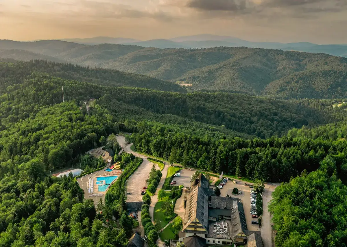 Malowniczy hotel spa w górach otoczony lasem, z basenem i zjeżdżalniami. Idealne miejsce na relaks.