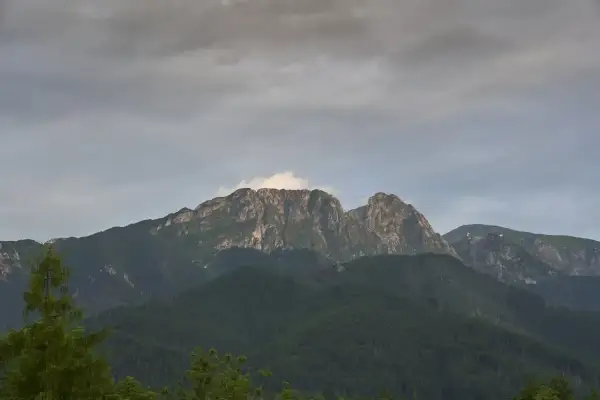 Giewont, śpiący rycerz Tatr, w chmurach. Góry o skalistych zboczach, porośnięte lasem.