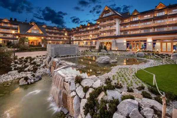 Elegancki hotel spa w górach z kaskadą wodną i stawem.