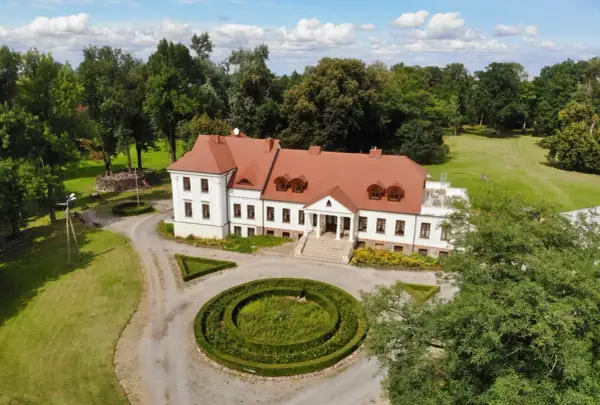 Piękny dwór stary Chotów otoczony zielenią, z zadbanym ogrodem i krętą ścieżką.