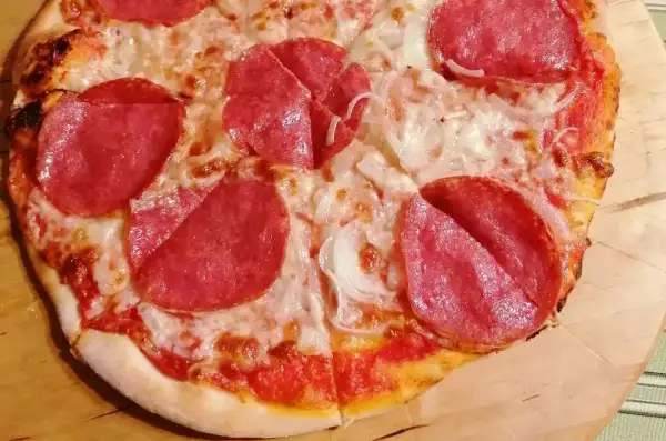 Pizza z pepperoni i cebulą, zrumieniona skórka, roztopiony ser.