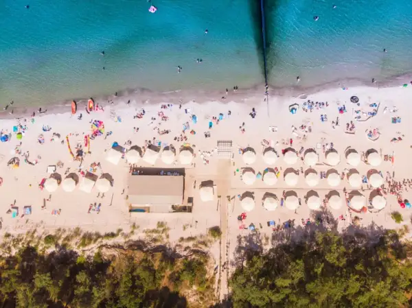 Idealne miejsce na wakacje: plaża z parasolami i ludźmi, idealna dla szukających najlepszych hoteli nad morzem z pełnym wyżywieniem.