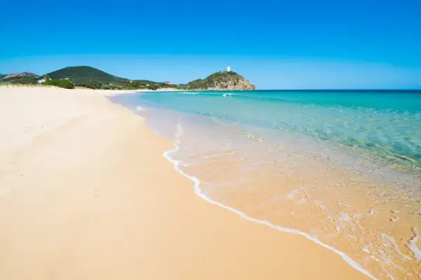 Piękne plaże Cagliari, z turkusową wodą i złotym piaskiem, zapraszają do relaksu. W oddali widać wieżę na wzgórzu.